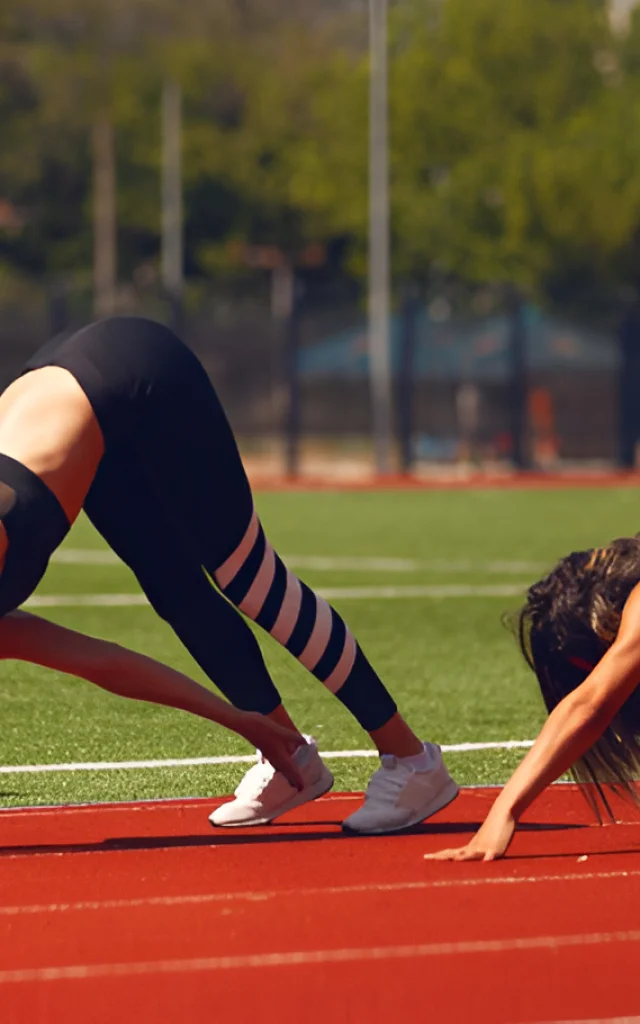 2 personnes faisant des étirements sur une piste de course