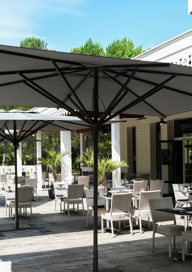 Terrasse extérieure d'un restaurant de Gujan-Mestras avec des tables dressées sous des parasols