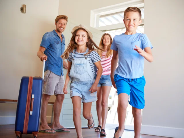 Famille entrant dans un hébergement touristique, avec les enfants qui rentrent en courant