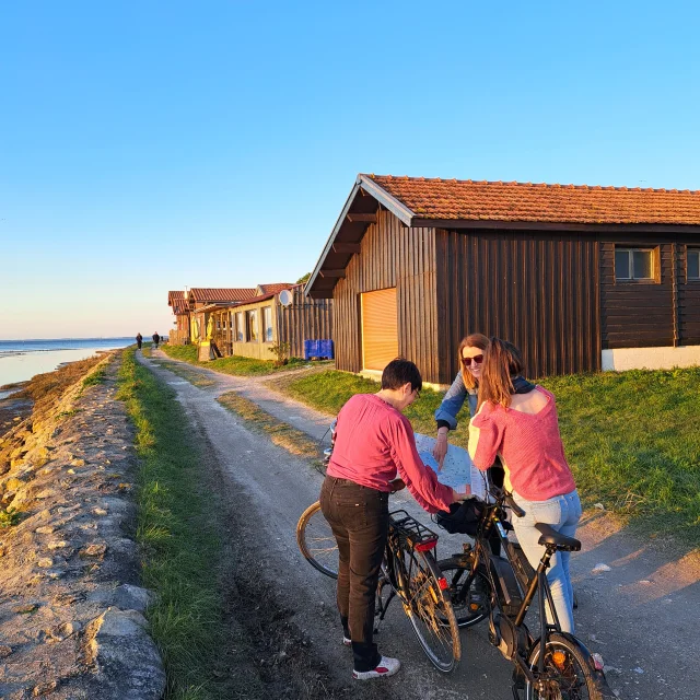 Des touristes à vélo sur le port de Larros qui sont en train de regarder la carte des déplacements pour connaître leur itinéraire