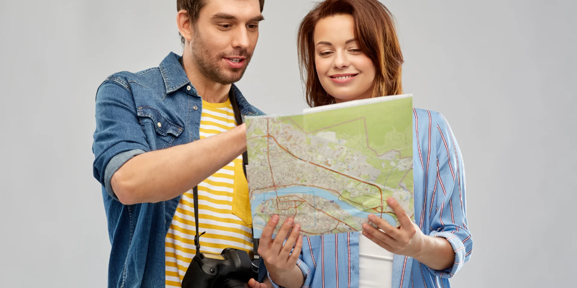 Un homme portant un appareil photo et une femme regardant une carte papier