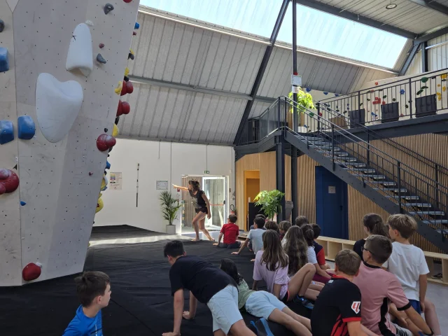 Groupe d'enfant en sortie scolaire écoutant les consignes d'un moniteur avant de commencer leur séance d'escalade.